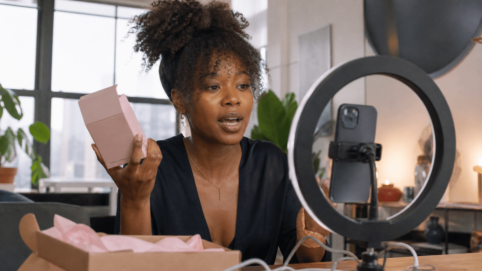 Black influencer filming an unboxing in a sunlit apartment