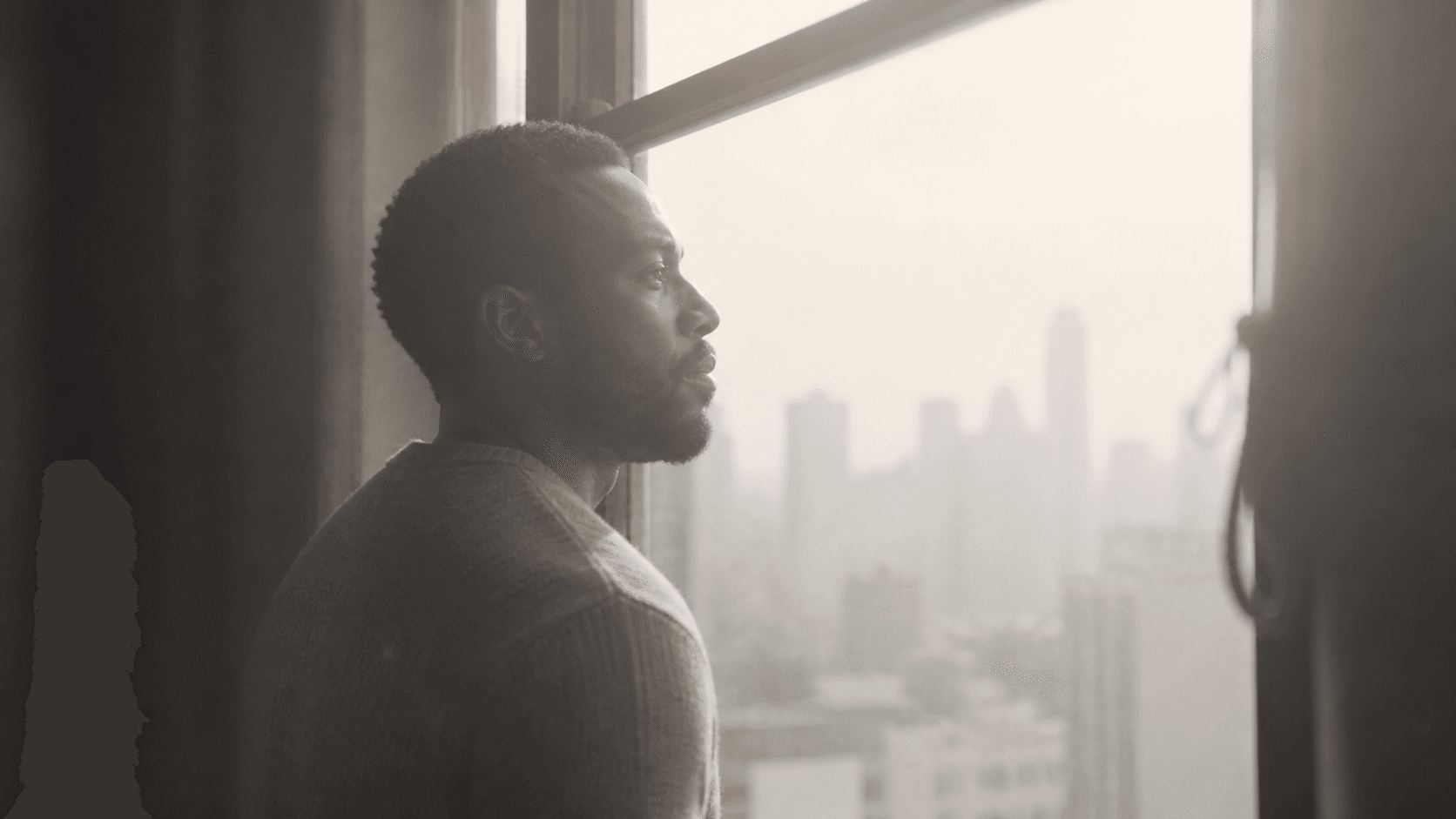 Black man looking out from a loft window